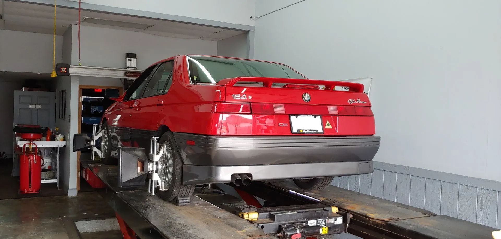 Red sports car on a lift in a garage.