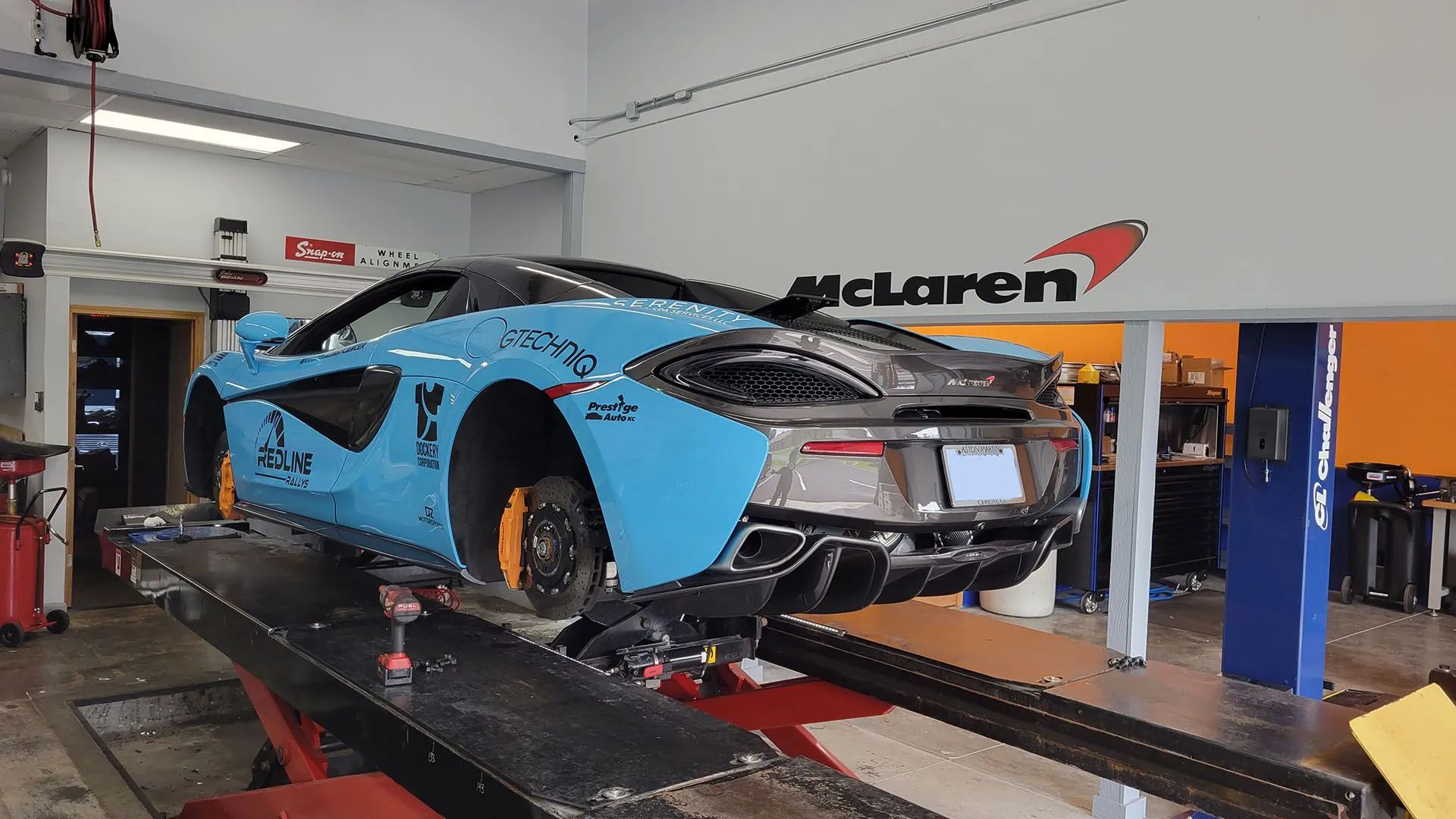 Blue McLaren sports car on a lift inside a McLaren service center.