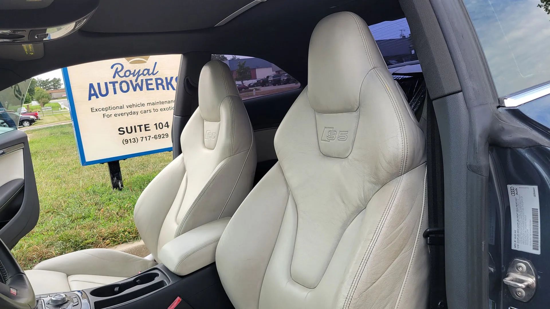 Cream leather interior of an Audi car with S5 logo on headrests, next to a sign for Royal Autowerks.