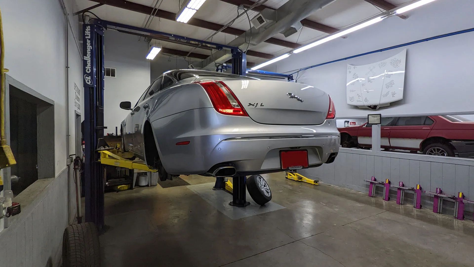 Silver car on a lift in a repair shop.