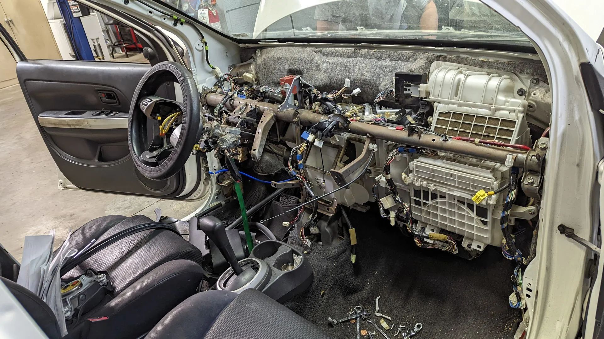 Car dashboard disassembled, revealing wires, components, and air conditioning unit.