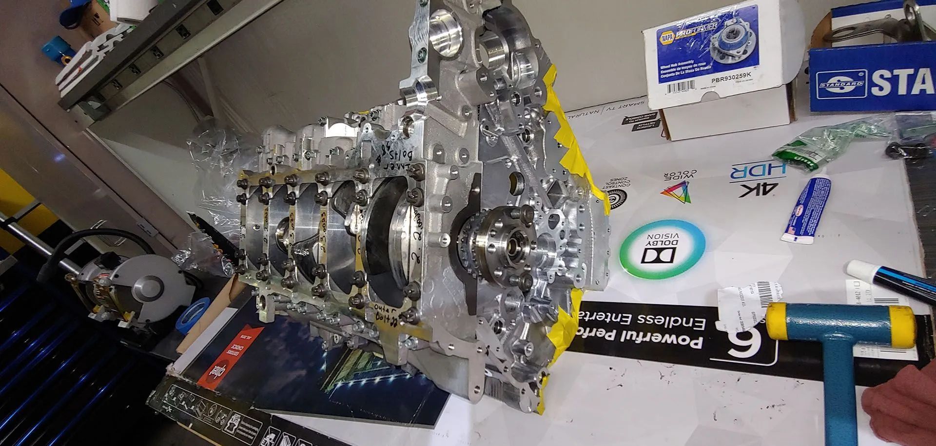 Engine parts laid out on a table. A blue and yellow hammer rests nearby.