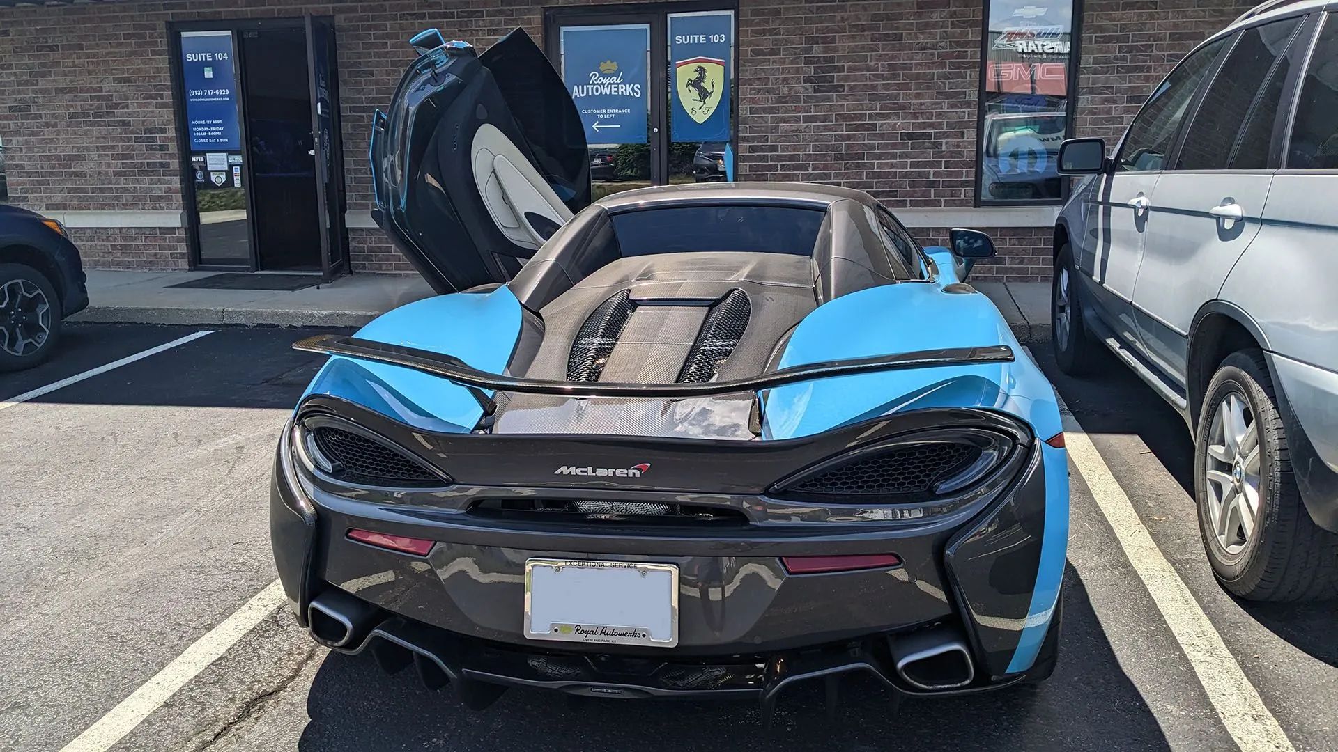 Blue and black McLaren sports car parked, rear view, door open.