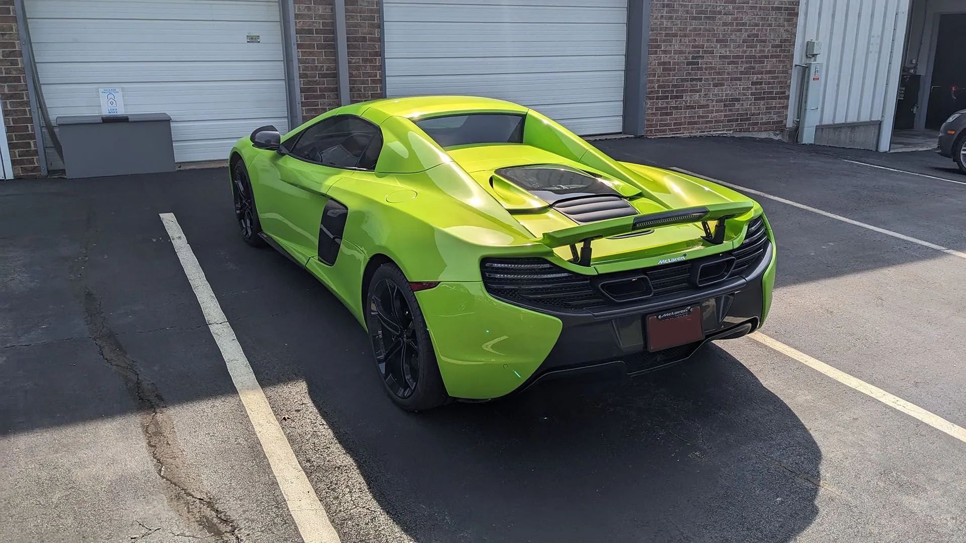 Lime green McLaren sports car parked in front of a building. Black wheels.