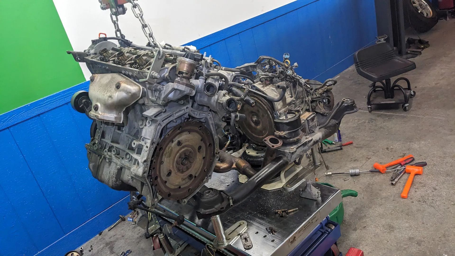 Engine removed from a vehicle, suspended from a chain in a garage.