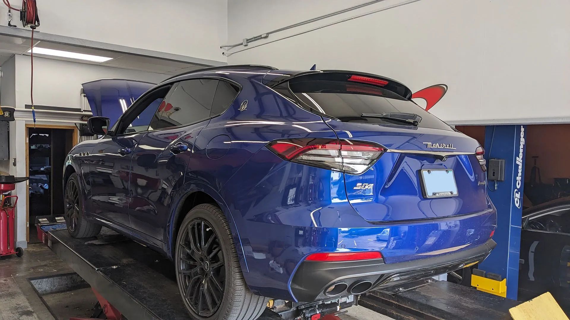 Blue Maserati SUV raised on a lift inside a repair shop.