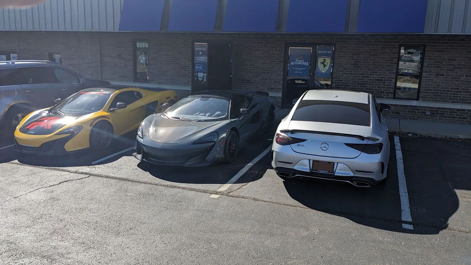 Yellow and gray sports cars parked outside a building on a sunny day.