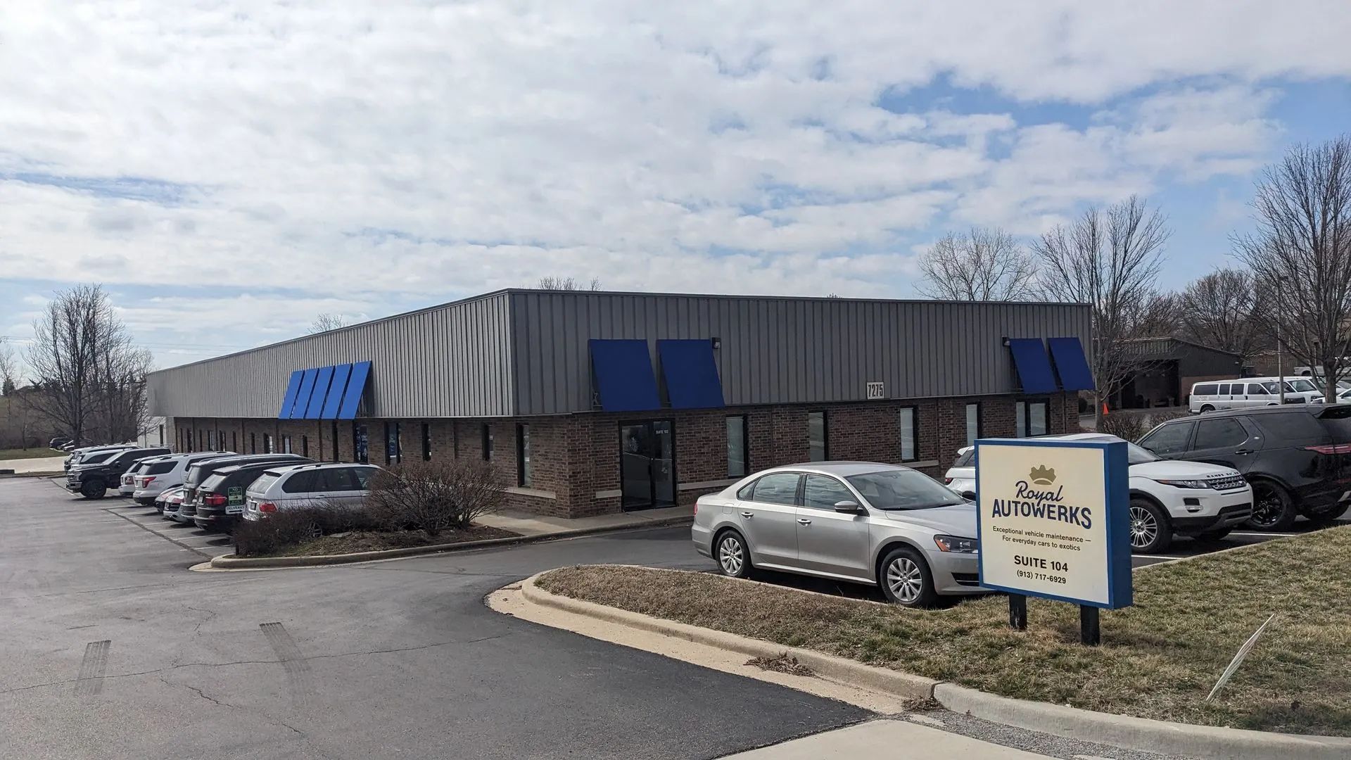Exterior view of a commercial building with cars parked in front and a sign that reads 