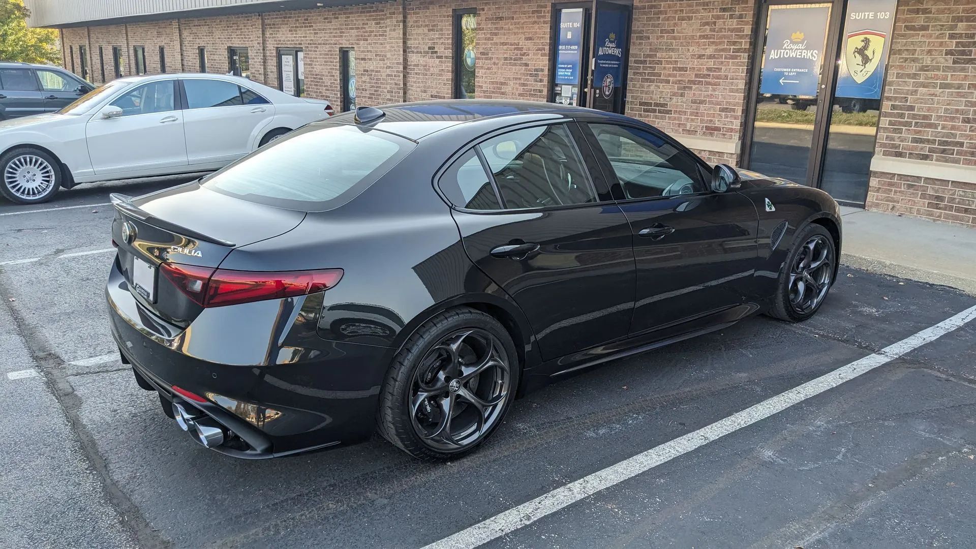 Black Alfa Romeo Giulia sedan parked in a parking space.