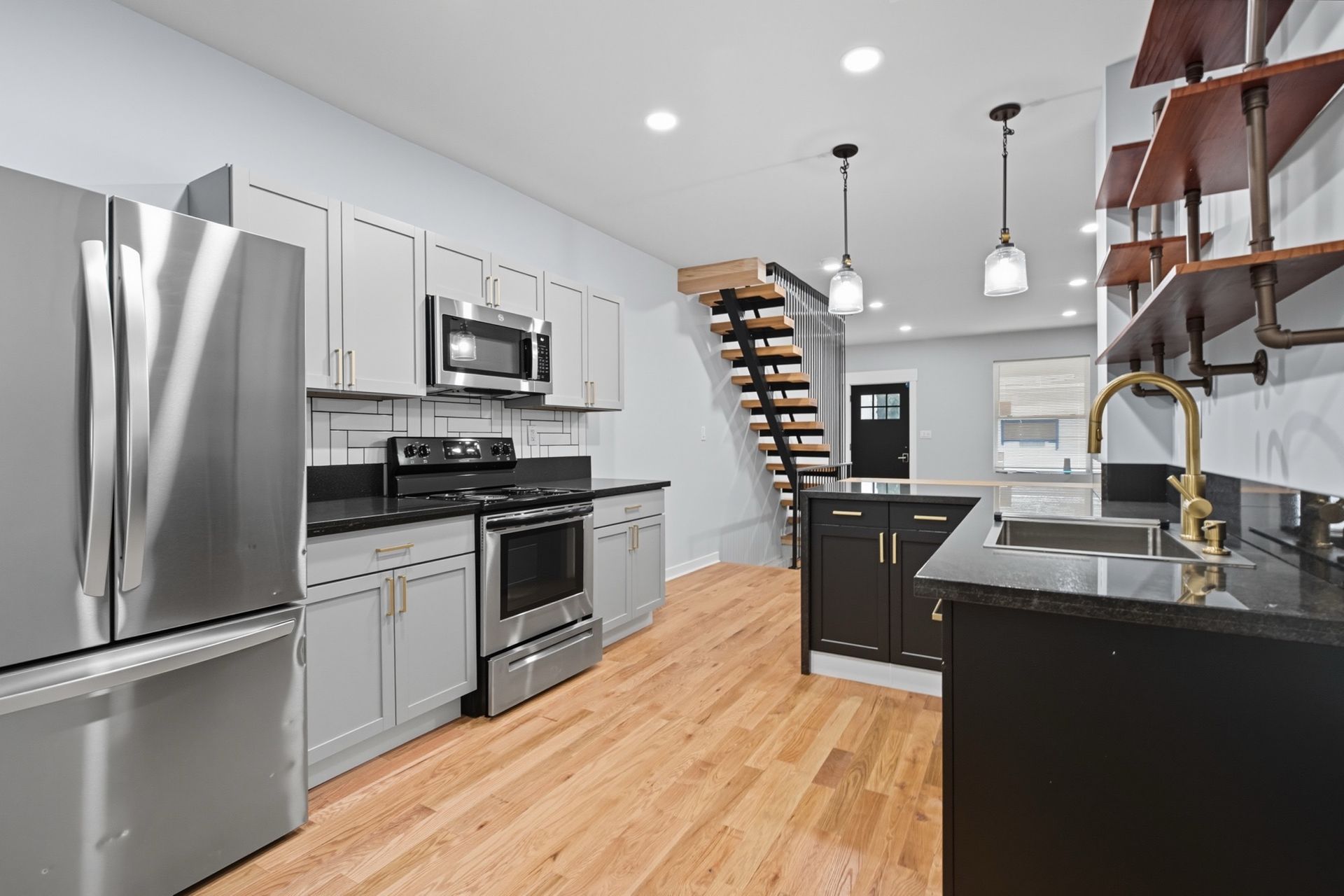 Modern kitchen with gray cabinets, stainless steel appliances, and wood flooring.