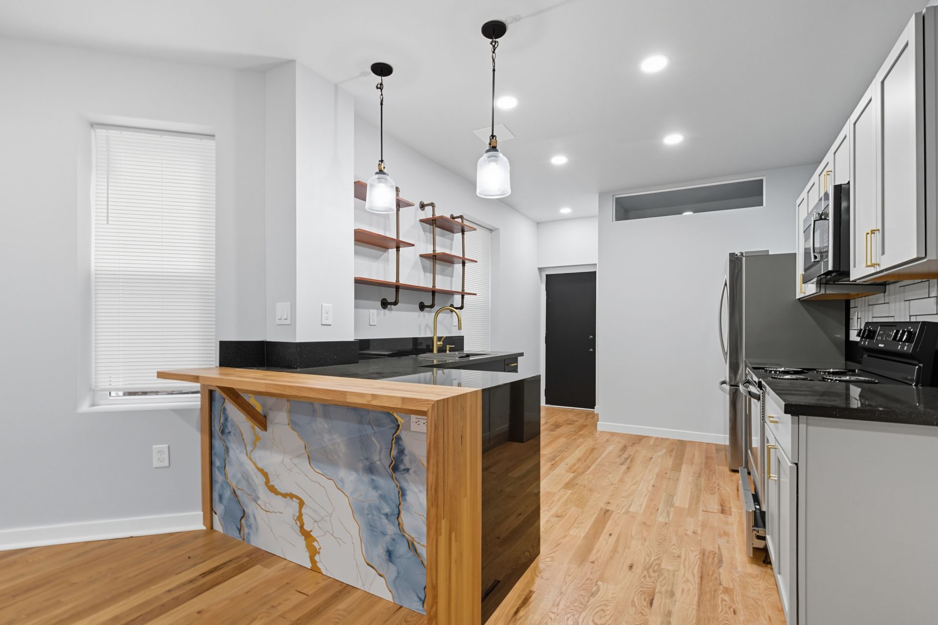 Modern kitchen with wood floors, white cabinets, and a unique island.