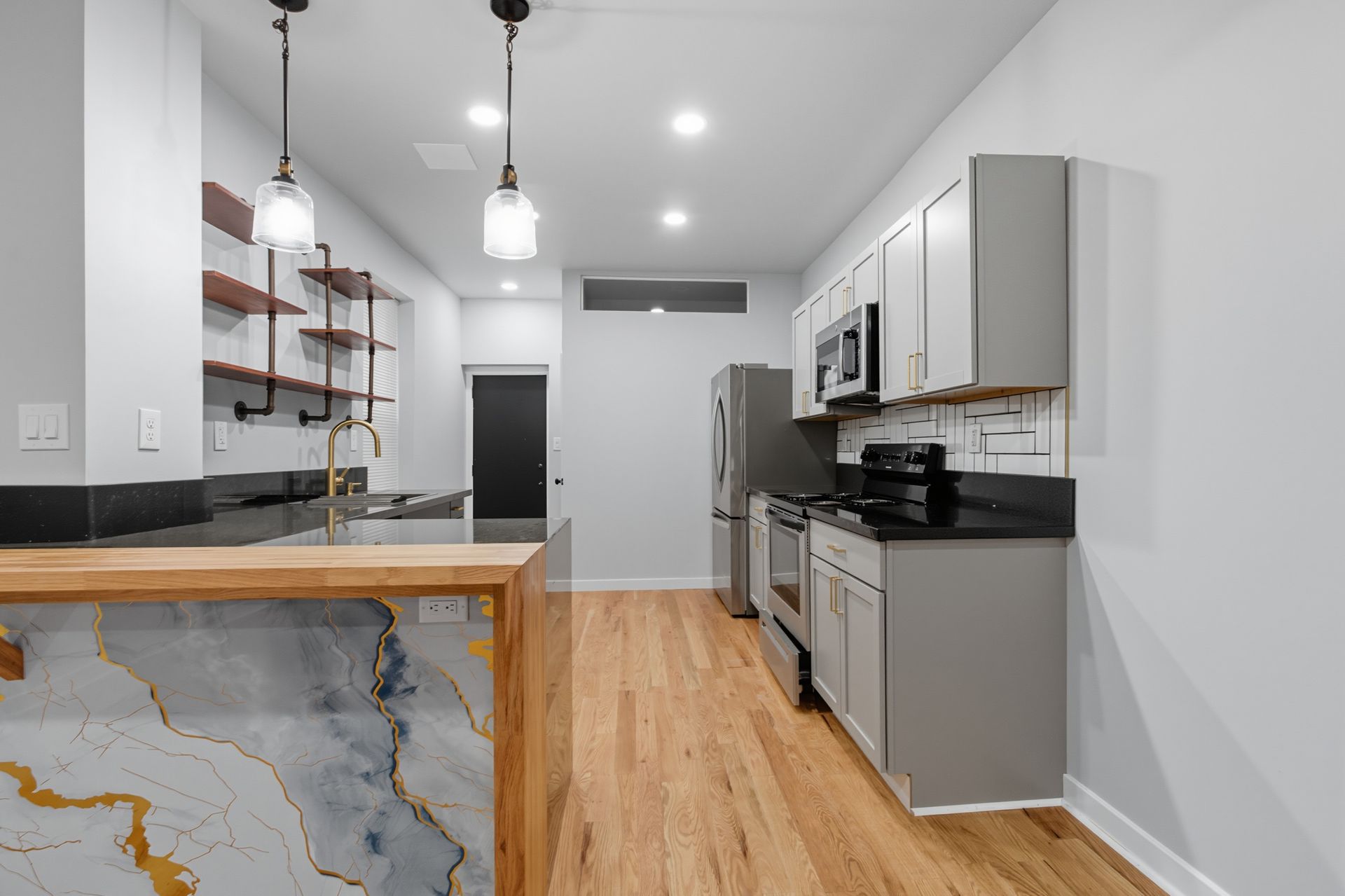 Modern kitchen with light wood floors, grey cabinets, and marble-look island.