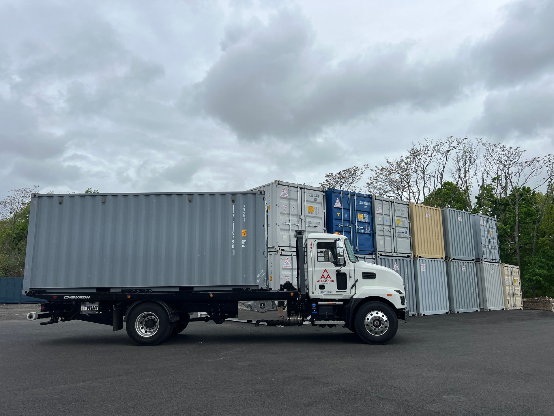 A truck is parked in front of a stack of shipping containers.