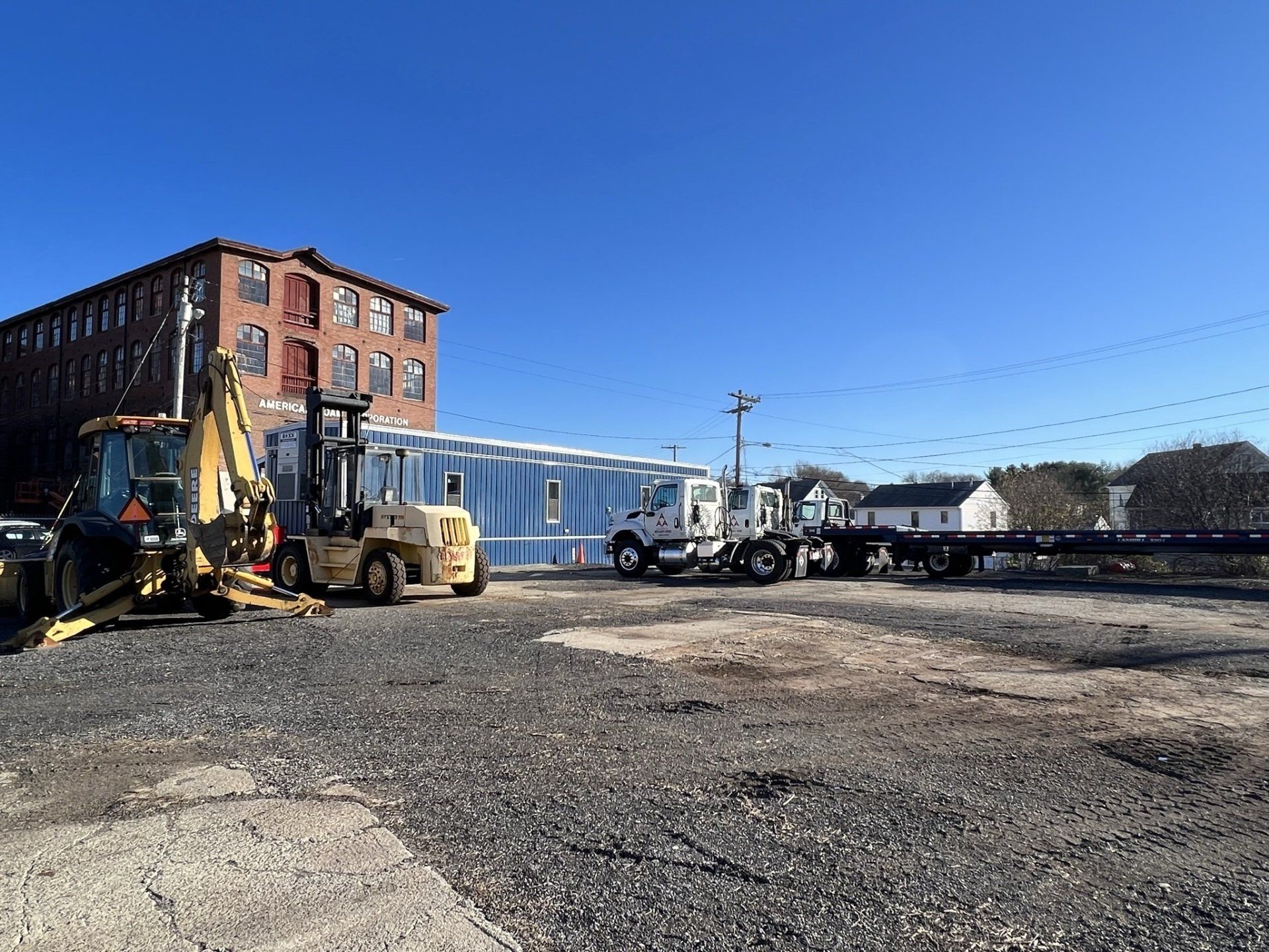 parking lot with brick building, blue trailer and yellow machine