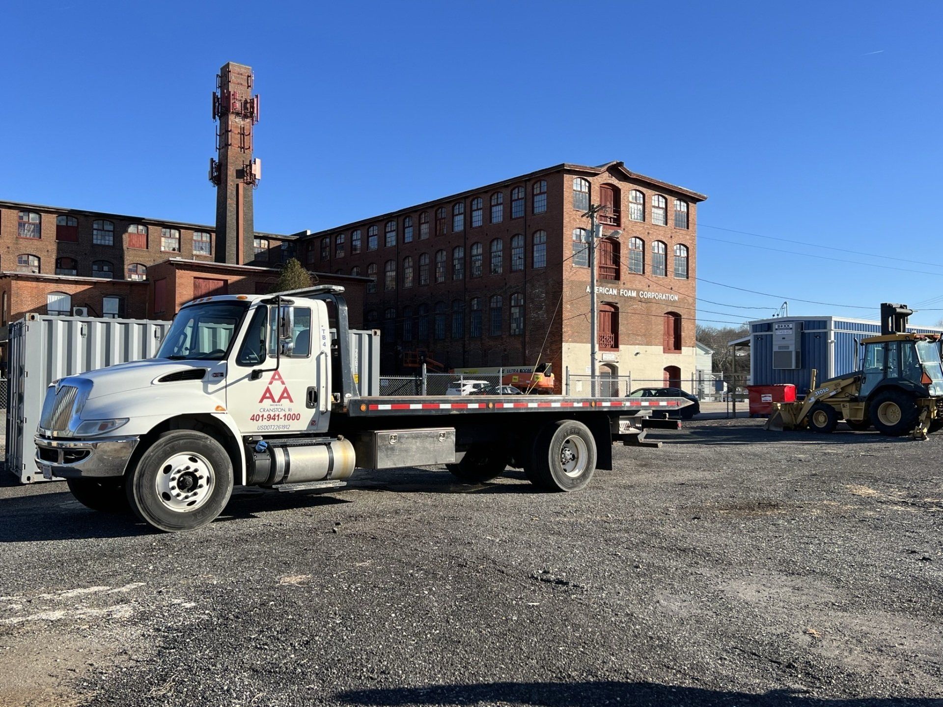 white flatbed truck with a brick building behind it