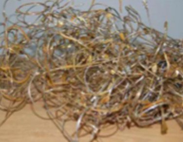 A pile of brass wire is sitting on a wooden table.