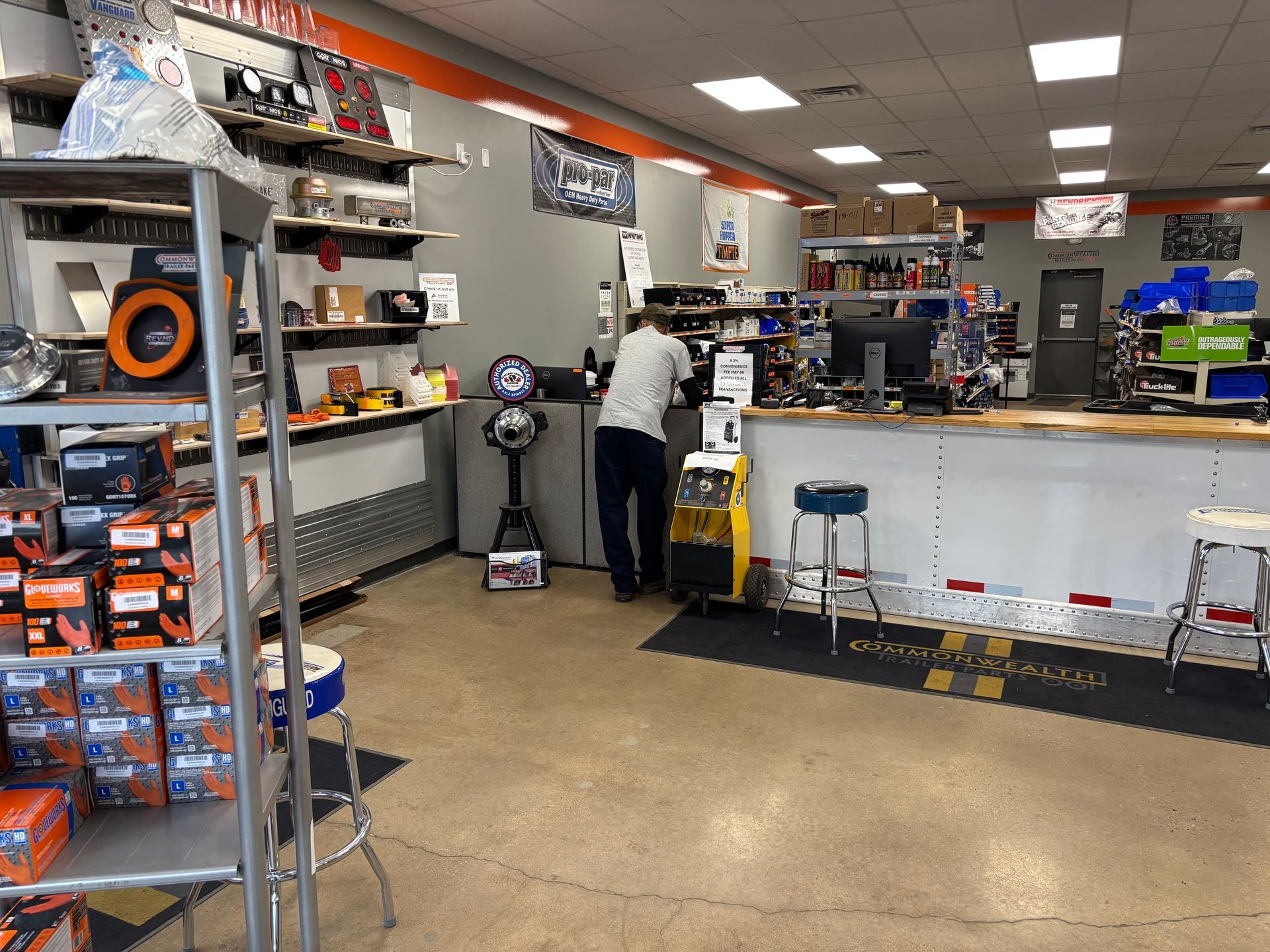 Auto parts store interior with a person at the counter and shelves of products on the left