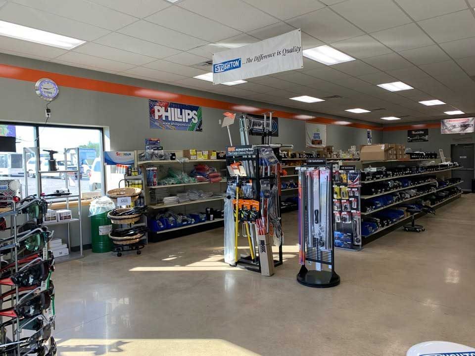 Interior of an auto parts store with aisles of shelves, retail displays, and signs for Philips and other brands.