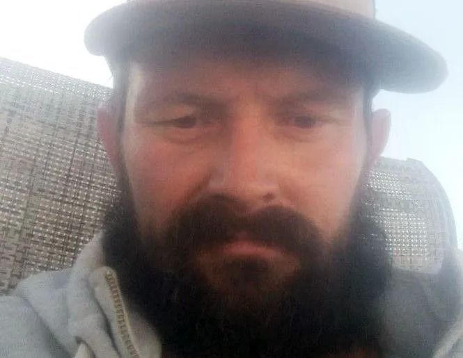Man with a full beard wearing a hat, looking at the camera.