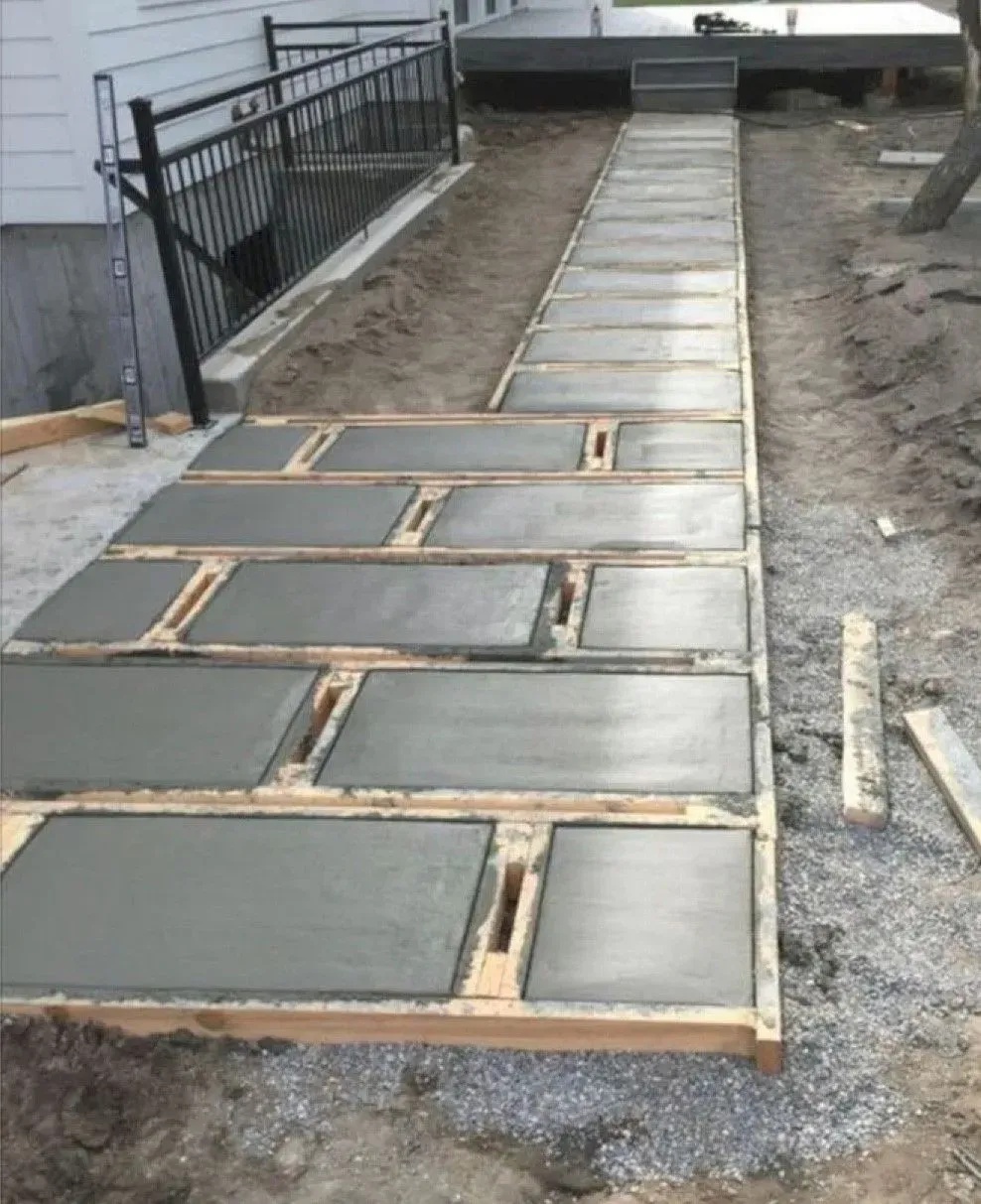 Freshly poured concrete slabs in wooden forms; pathway leading up to a deck.