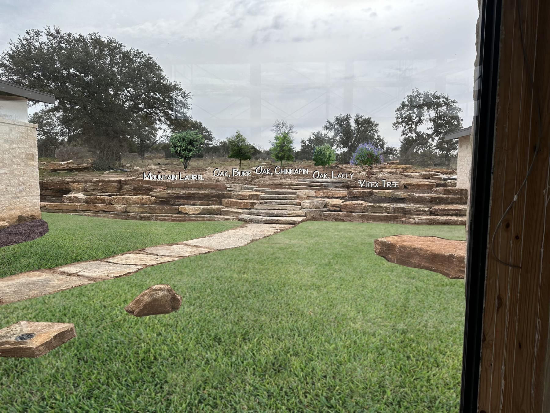 Stone terraced yard with green grass, and stone pathway under an overcast sky.