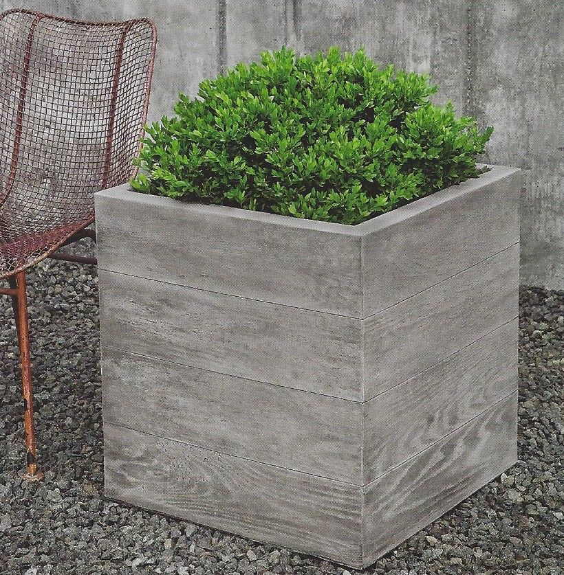 A planter with a plant in it sits next to a chair
