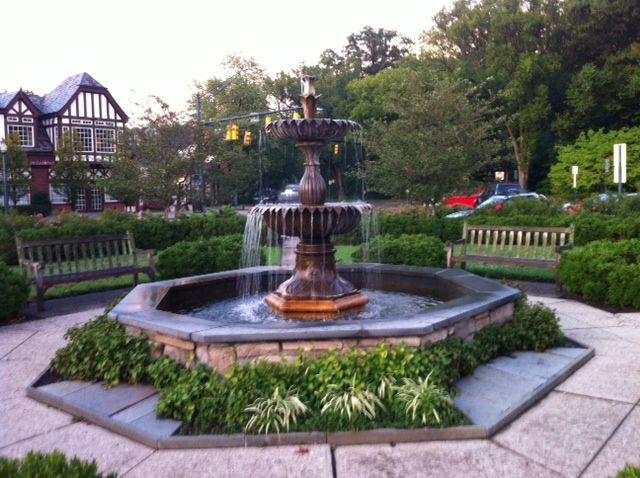 A fountain in a park with a bench in the background
