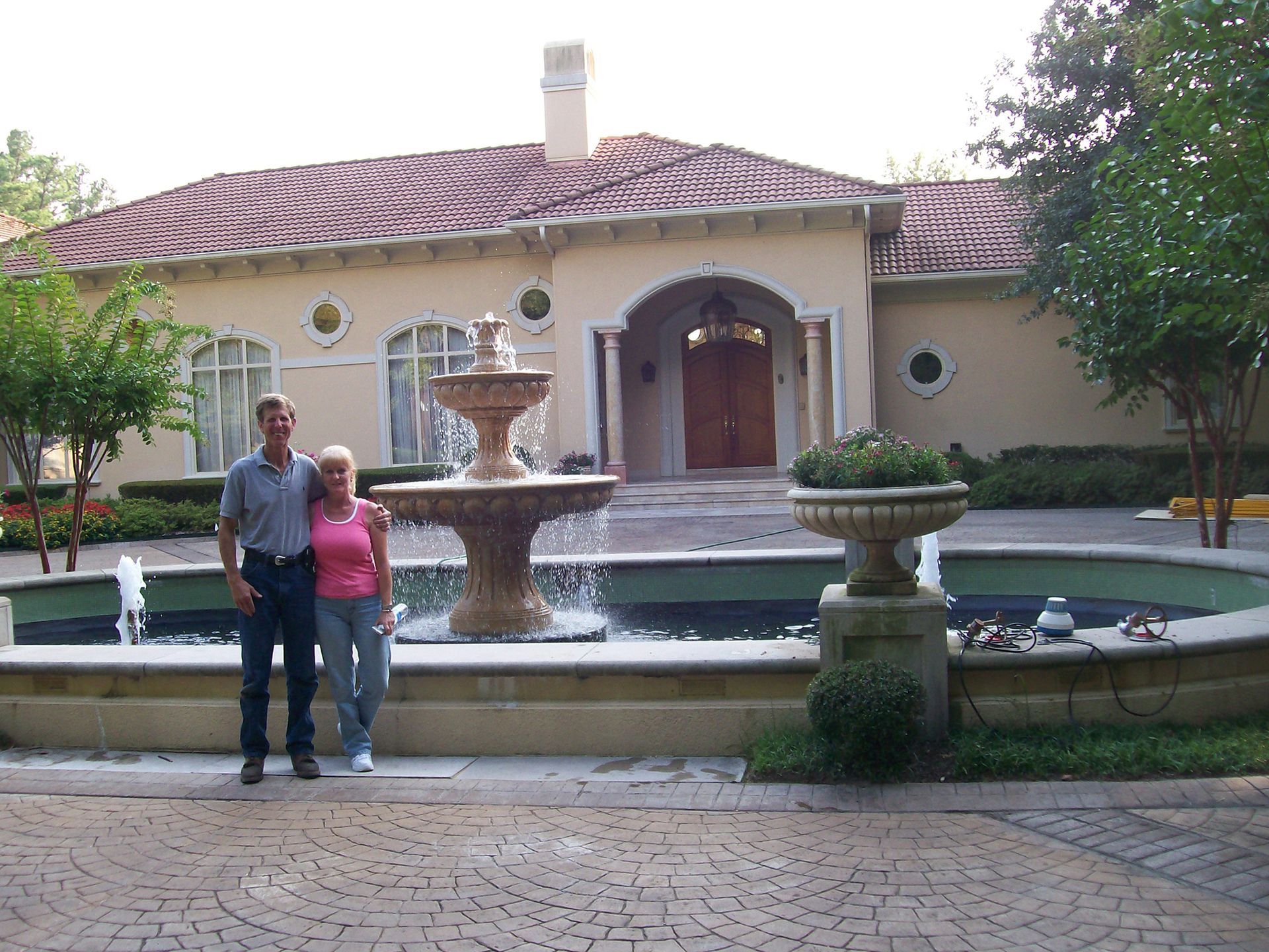 A couple standing in front of a fountain in front of a house