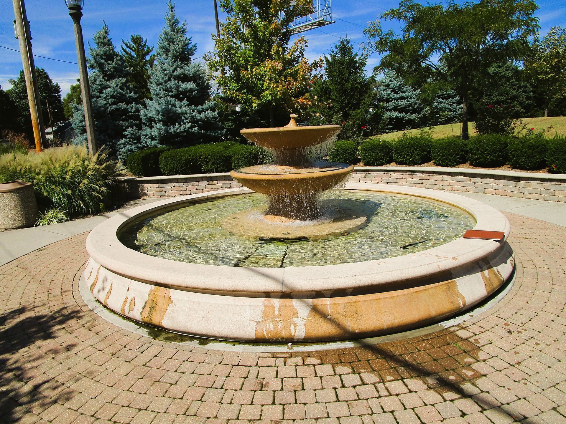 A fountain in a park with trees in the background