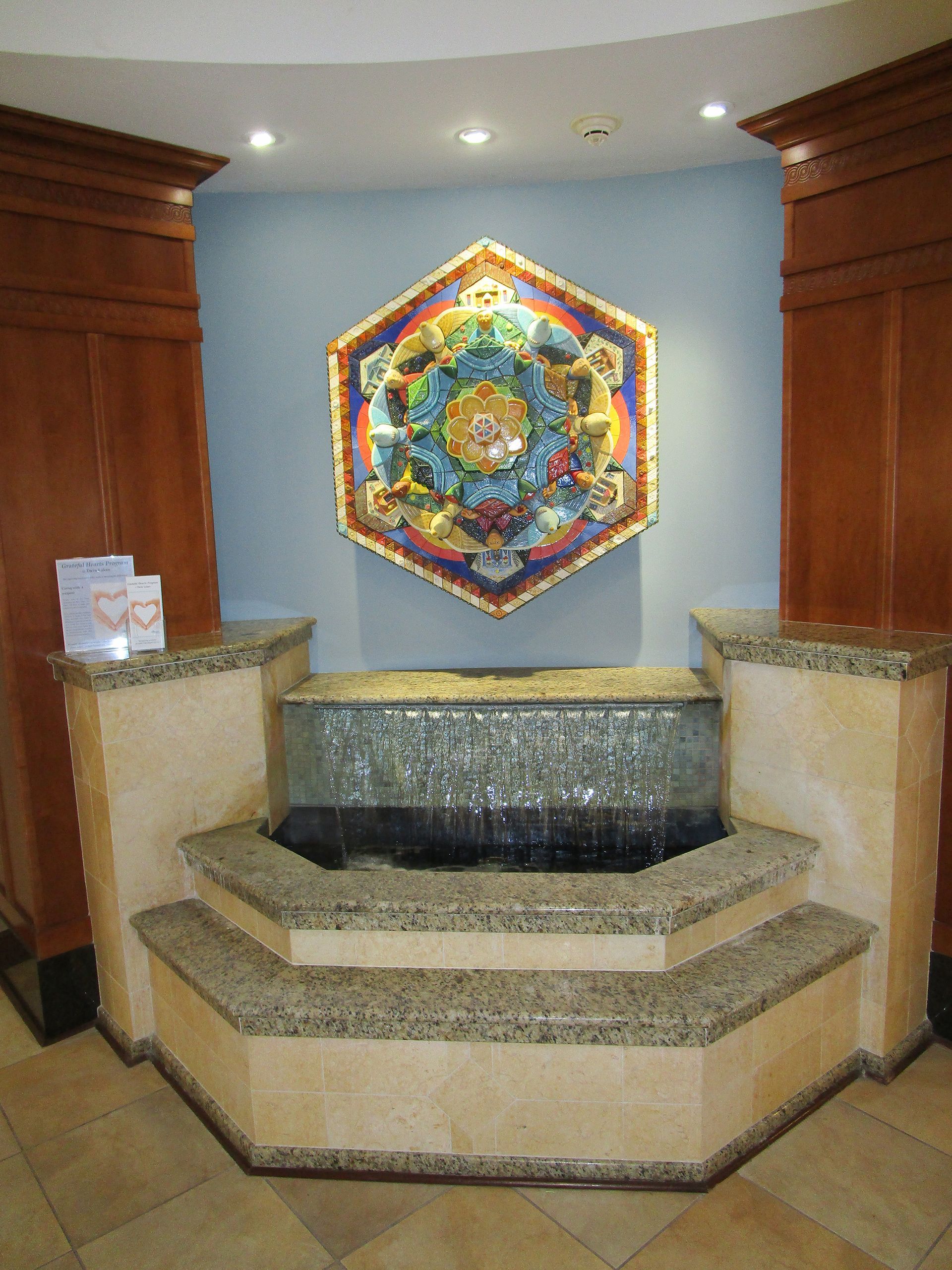 A fountain with a painting on the wall above it