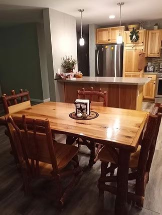 A rustic dining set with a wooden table and matching chairs sits in front of a kitchen island and cabinetry.