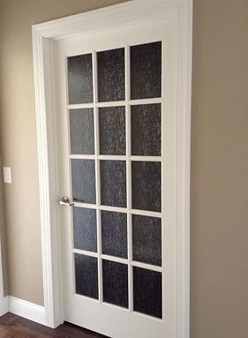 A white 15-pane glass door with textured, translucent panels, installed in a beige room with white trim.