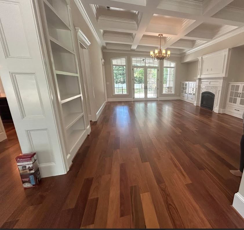 Spacious room with dark hardwood floors, white built-in shelving, a coffered ceiling, and a fireplace.