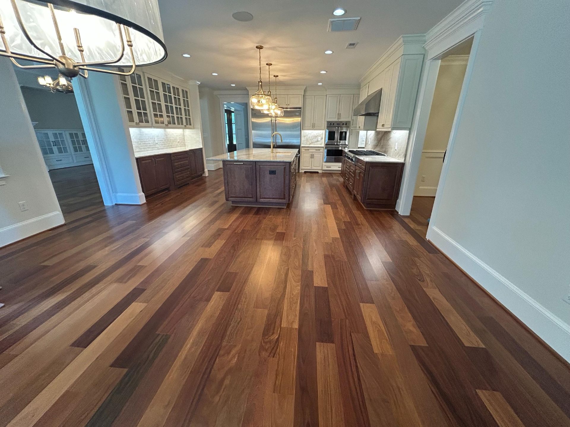 A bright, modern kitchen featuring dark wood cabinetry, a central island, and polished hardwood floors.