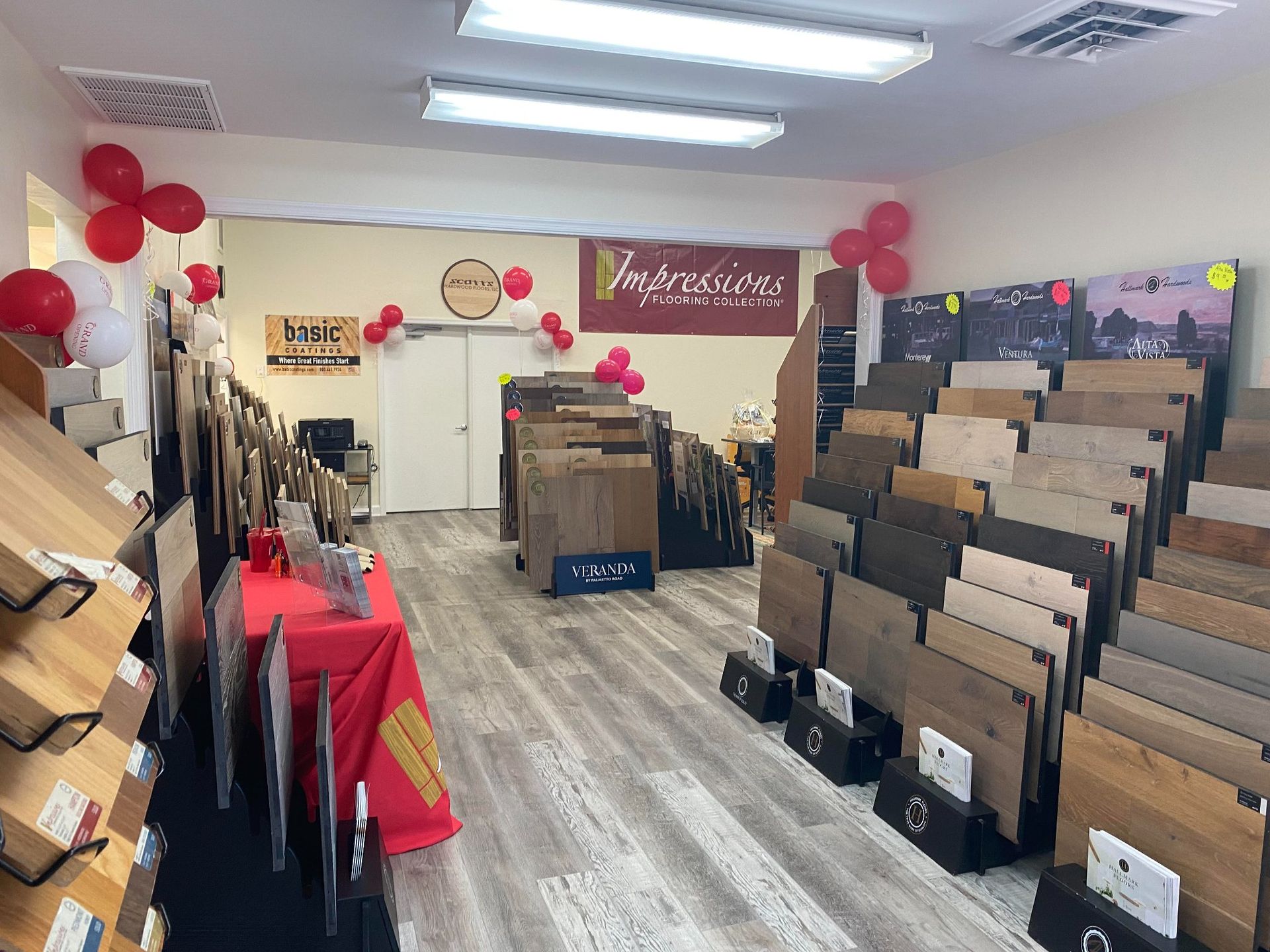 A showroom interior featuring numerous flooring samples displayed on racks, with red balloons decorating the room.