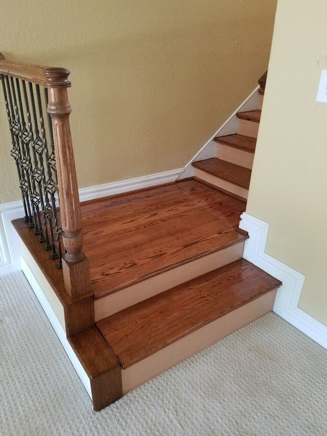 Staircase starting with two hardwood steps leading to carpeted stairs, featuring a wood and wrought iron railing.