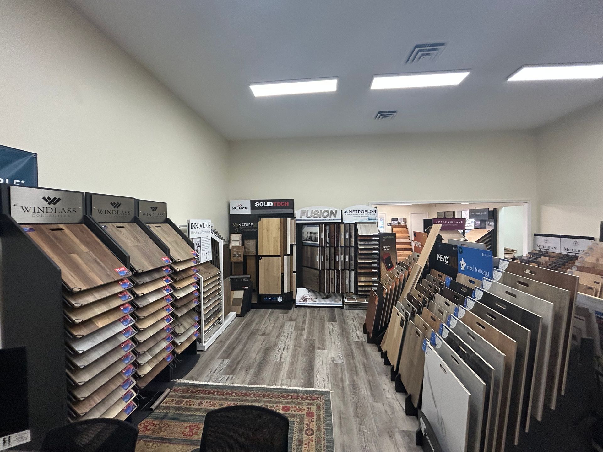 A flooring store showroom featuring numerous upright racks displaying various wood and tile sample boards.