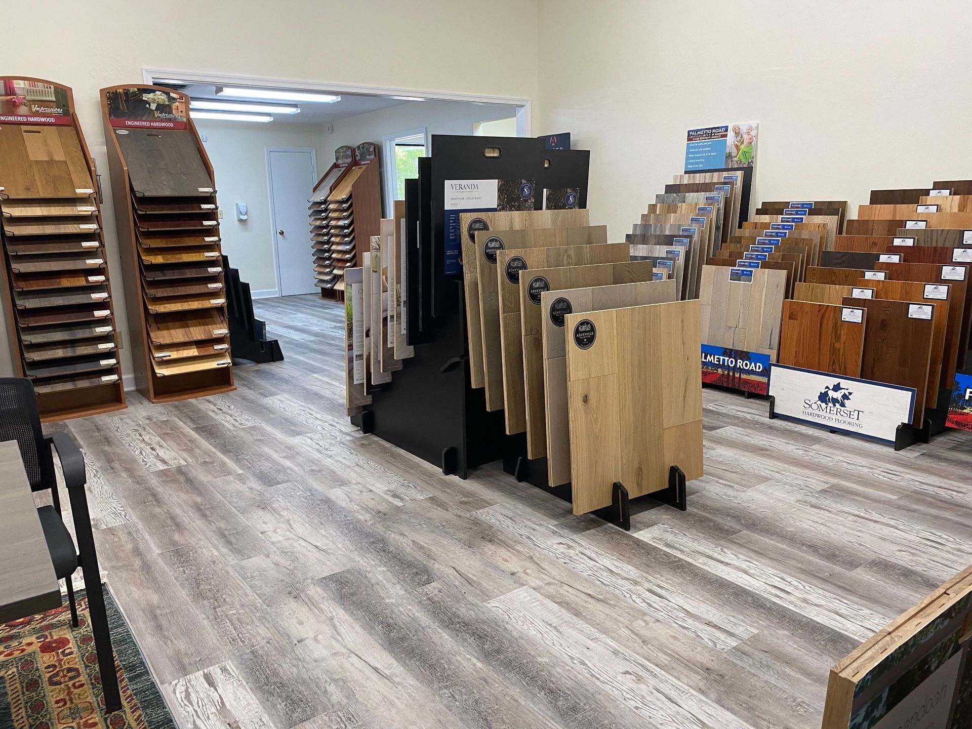 A flooring showroom featuring numerous standing display racks filled with various wood and laminate plank samples.