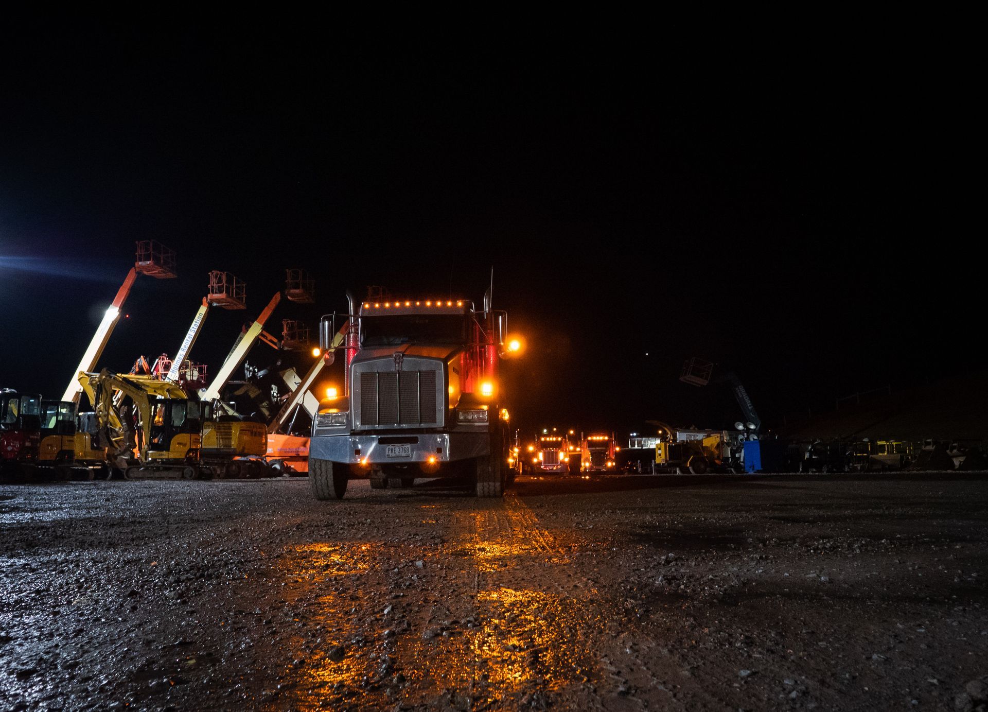 A semi truck is parked in a parking lot at night.