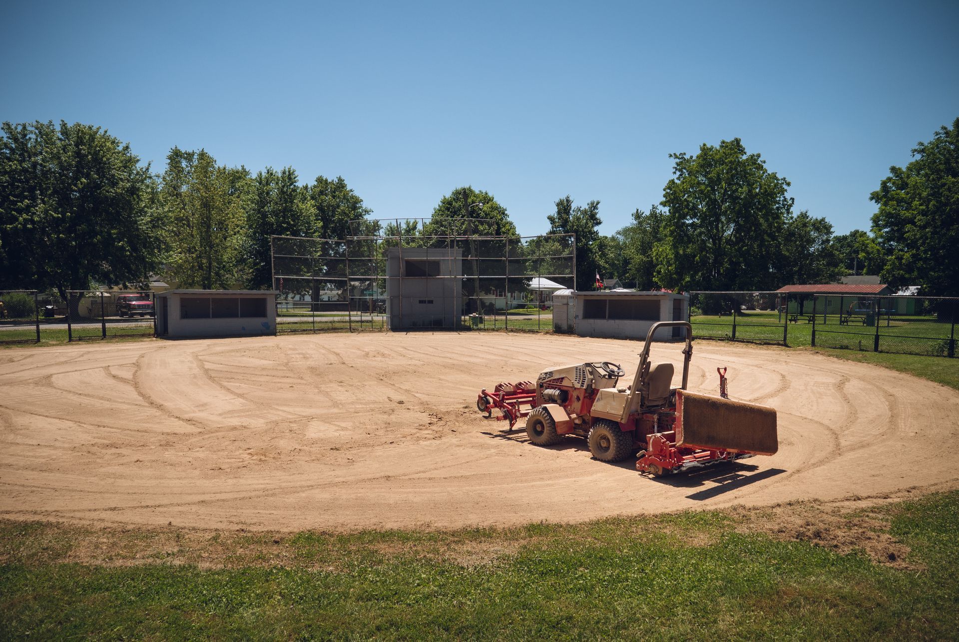 A tractor is sitting in the middle of a baseball field.
