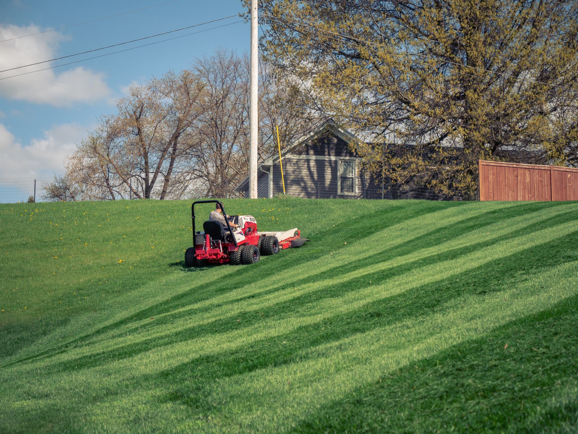 A person is mowing a lush green lawn with a lawn mower.