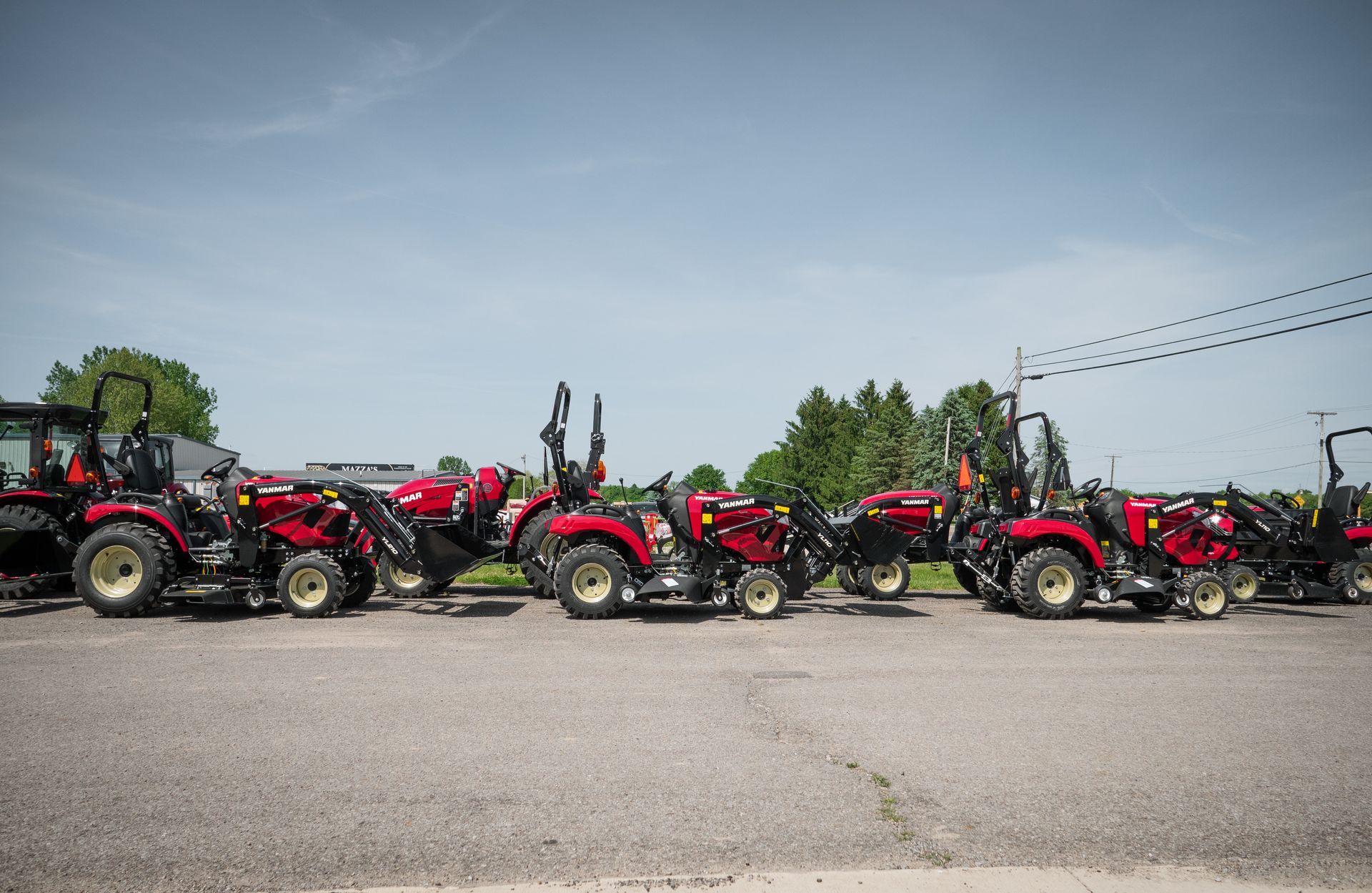 A row of red tractors are parked on the side of the road.