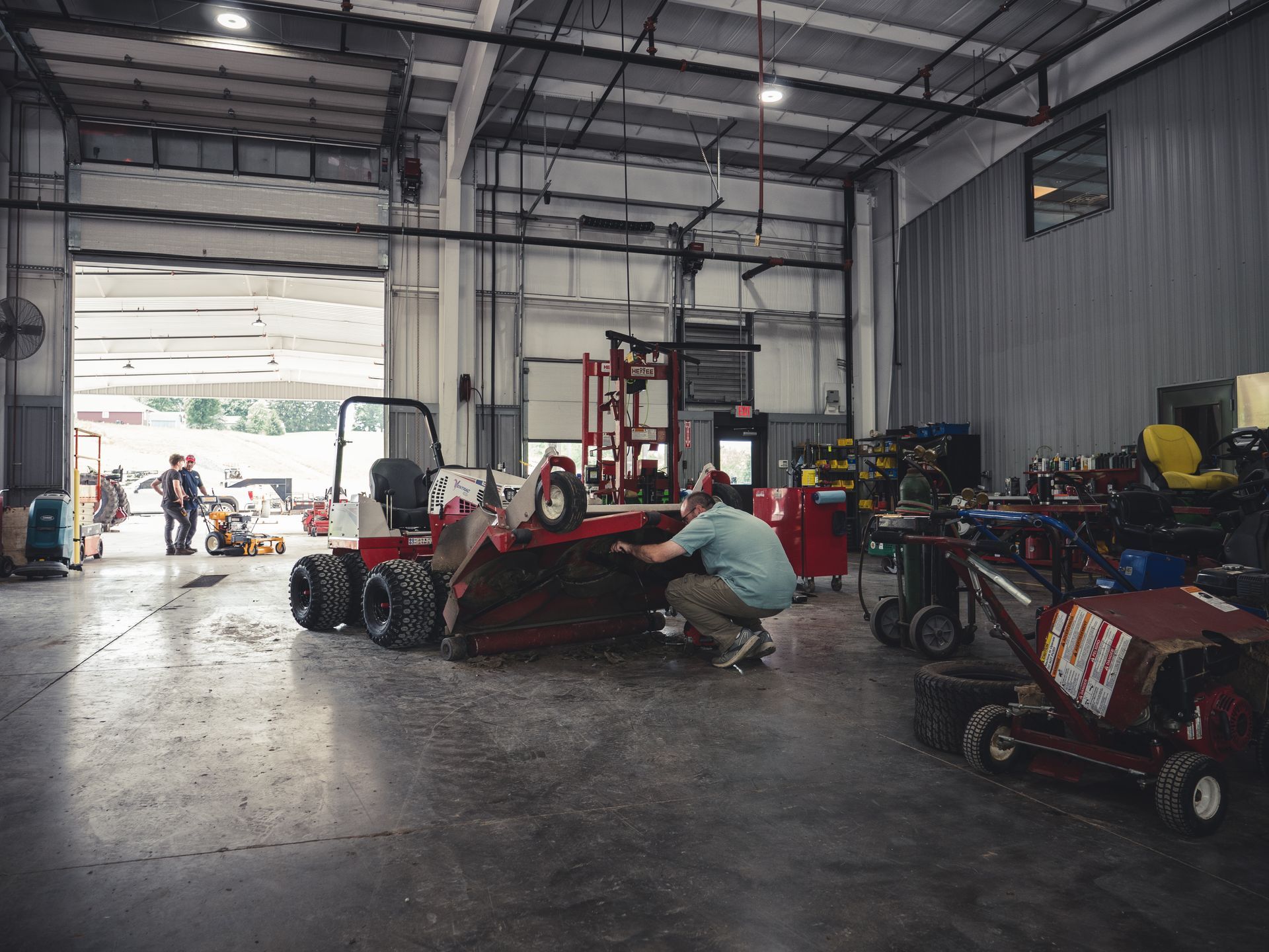 A man is working on a lawn mower in a garage.
