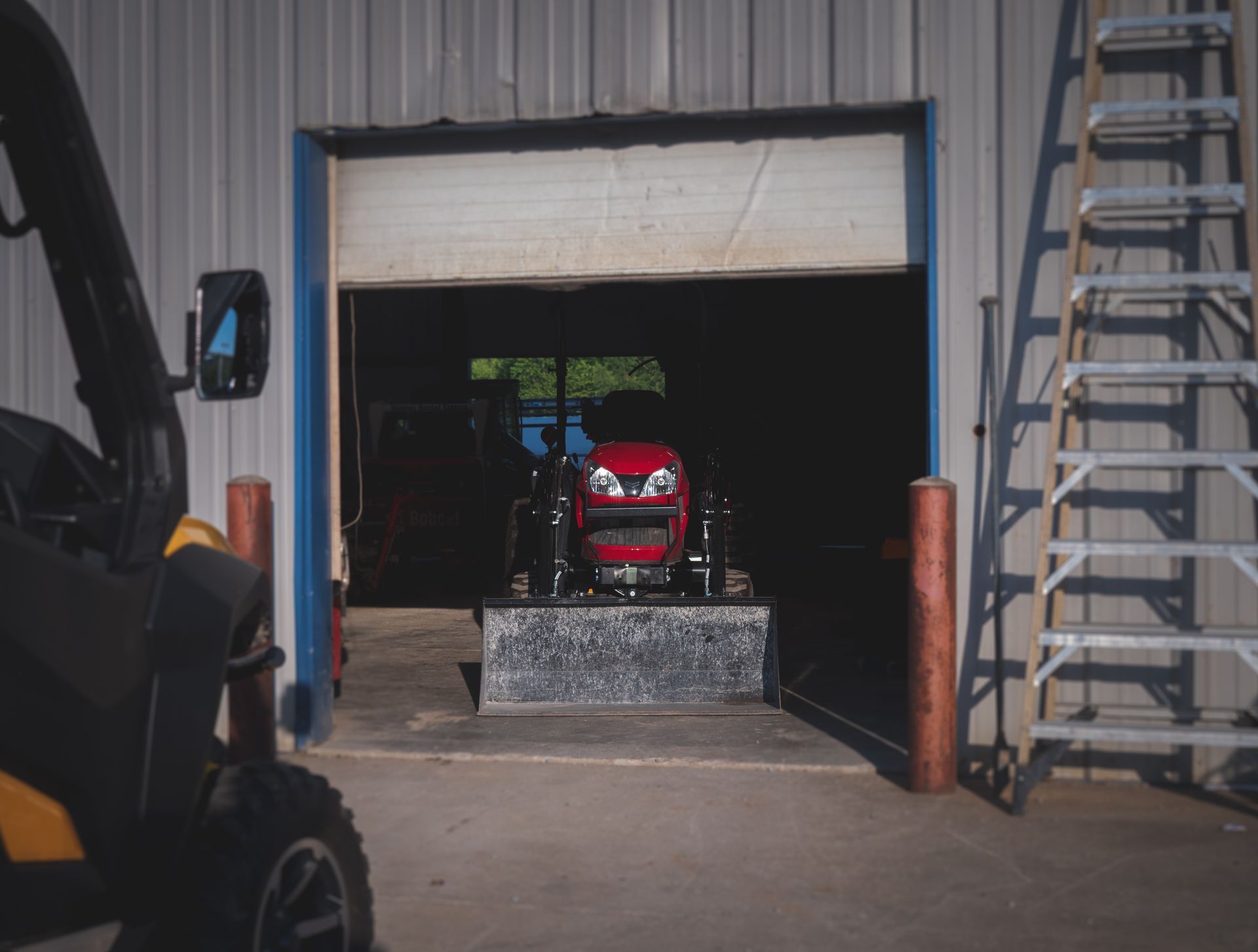 A red atv is parked in a garage next to a ladder.