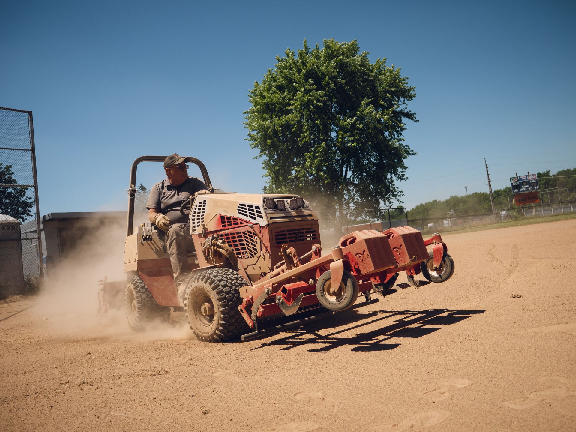 A man is driving a tractor on a dirt road.