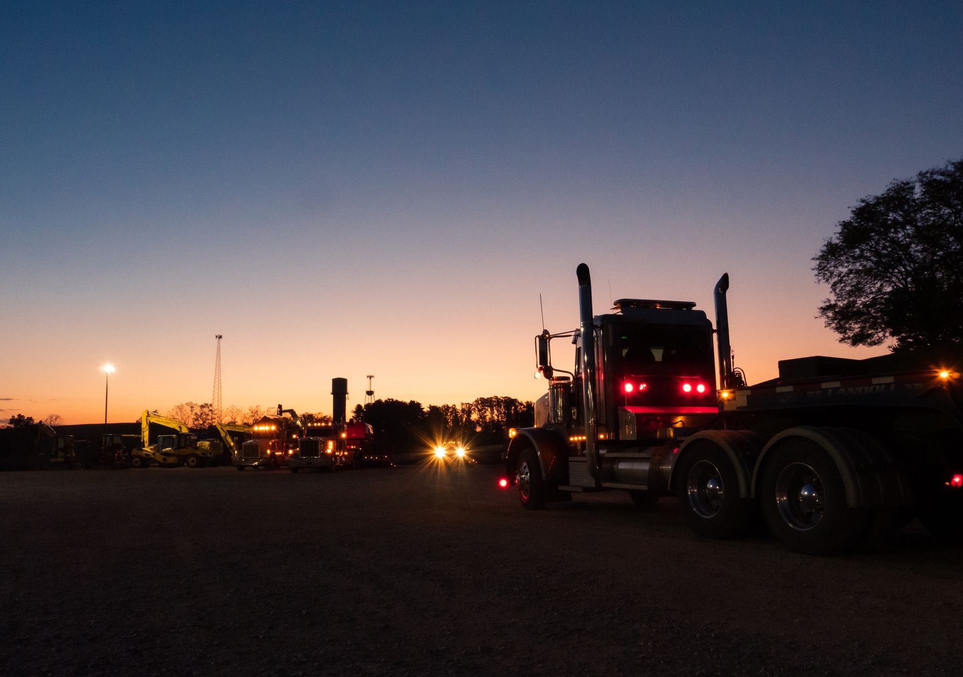 A semi truck is parked in a parking lot at night.