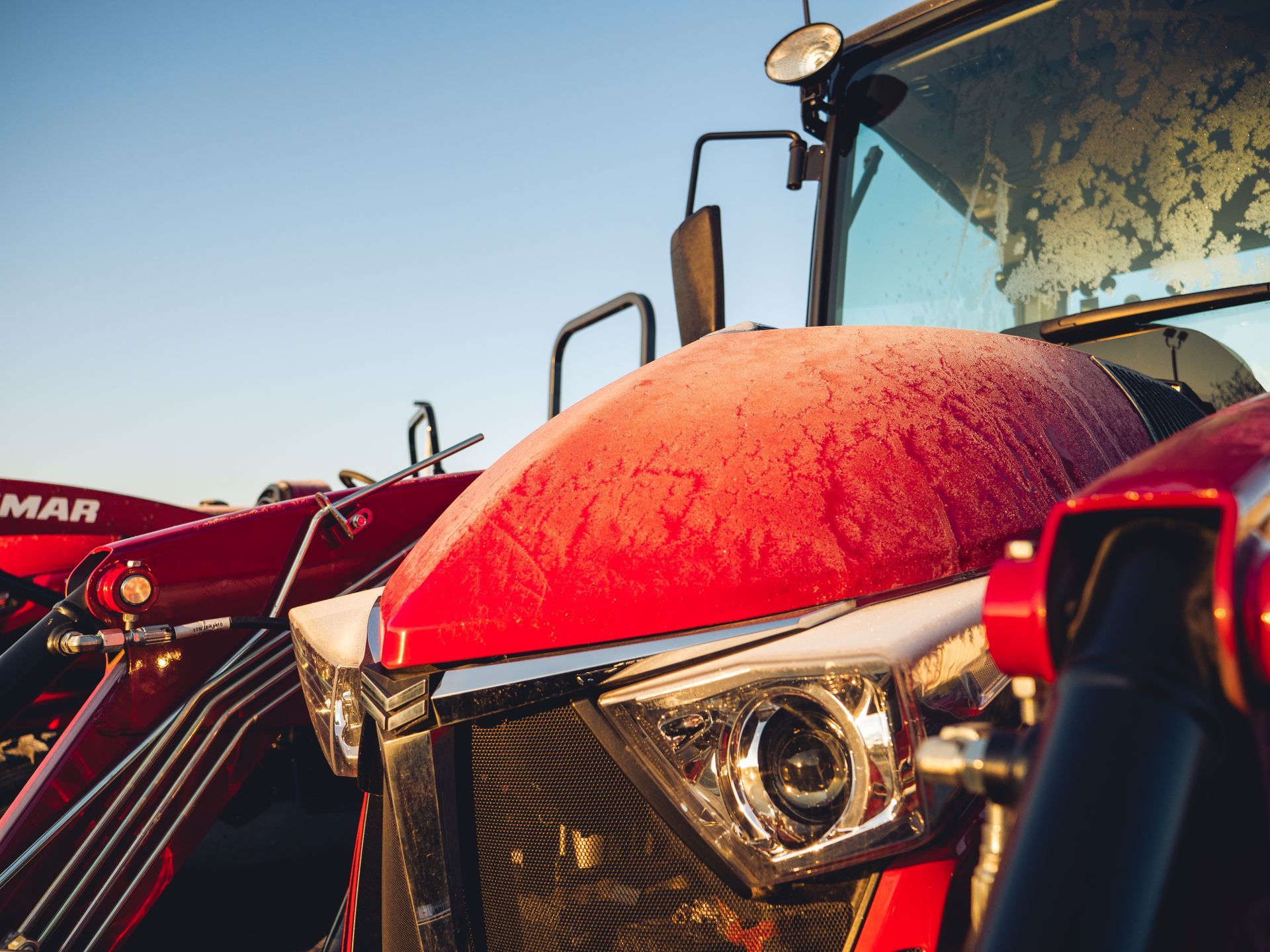 A close up of a red tractor covered in snow