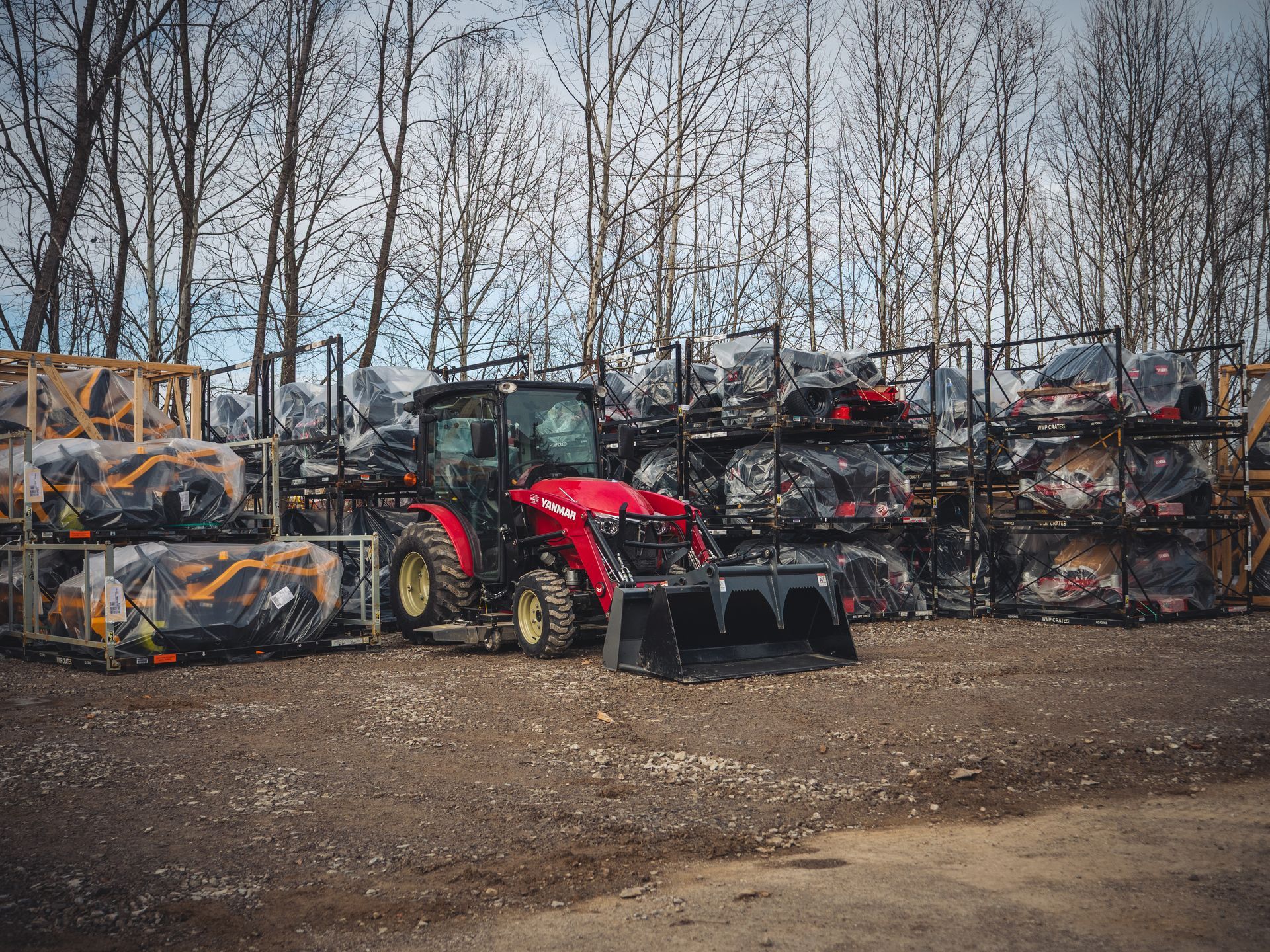 A red tractor is parked in front of a pile of tires.