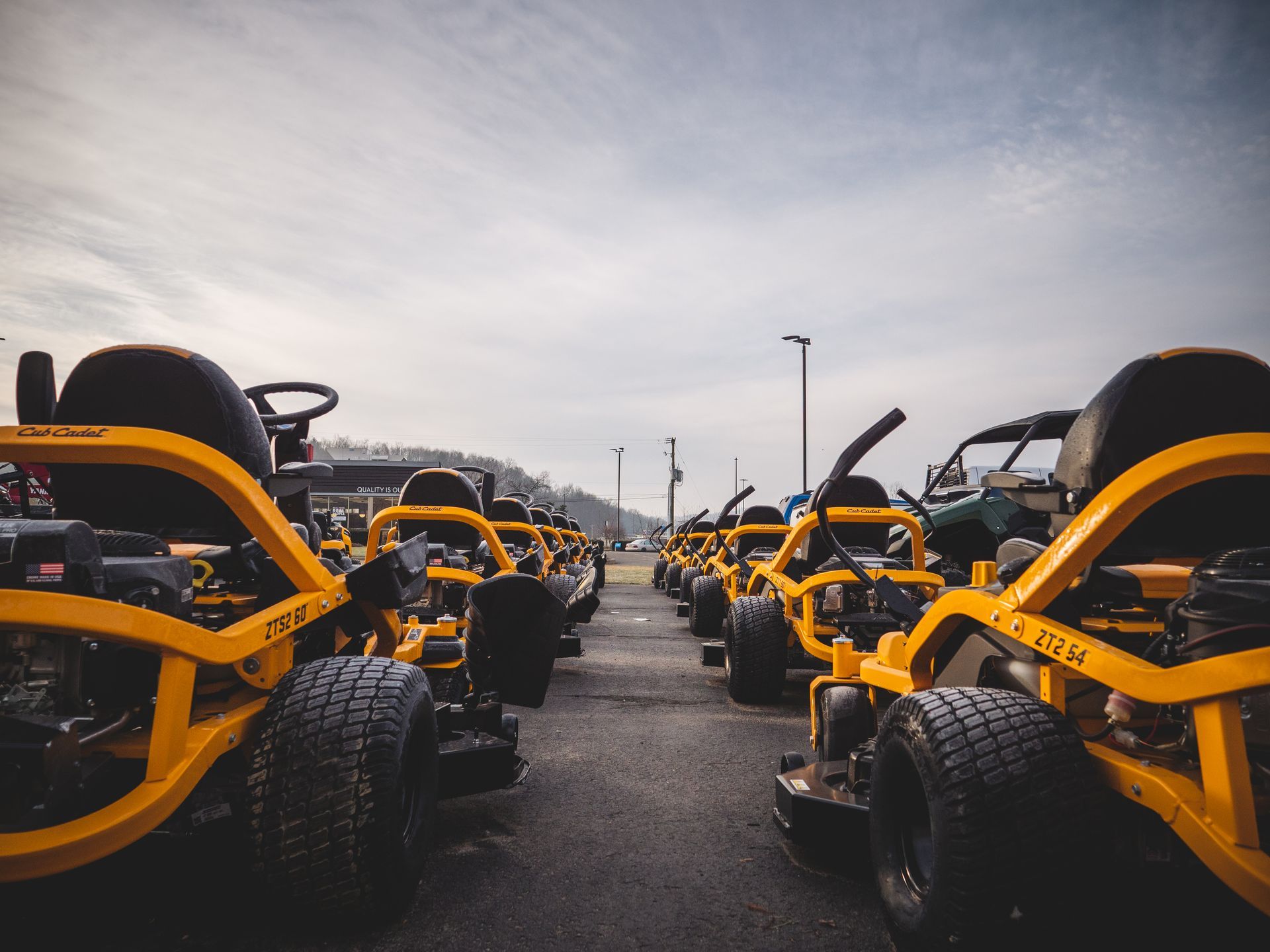 A row of yellow go karts are parked in a parking lot.