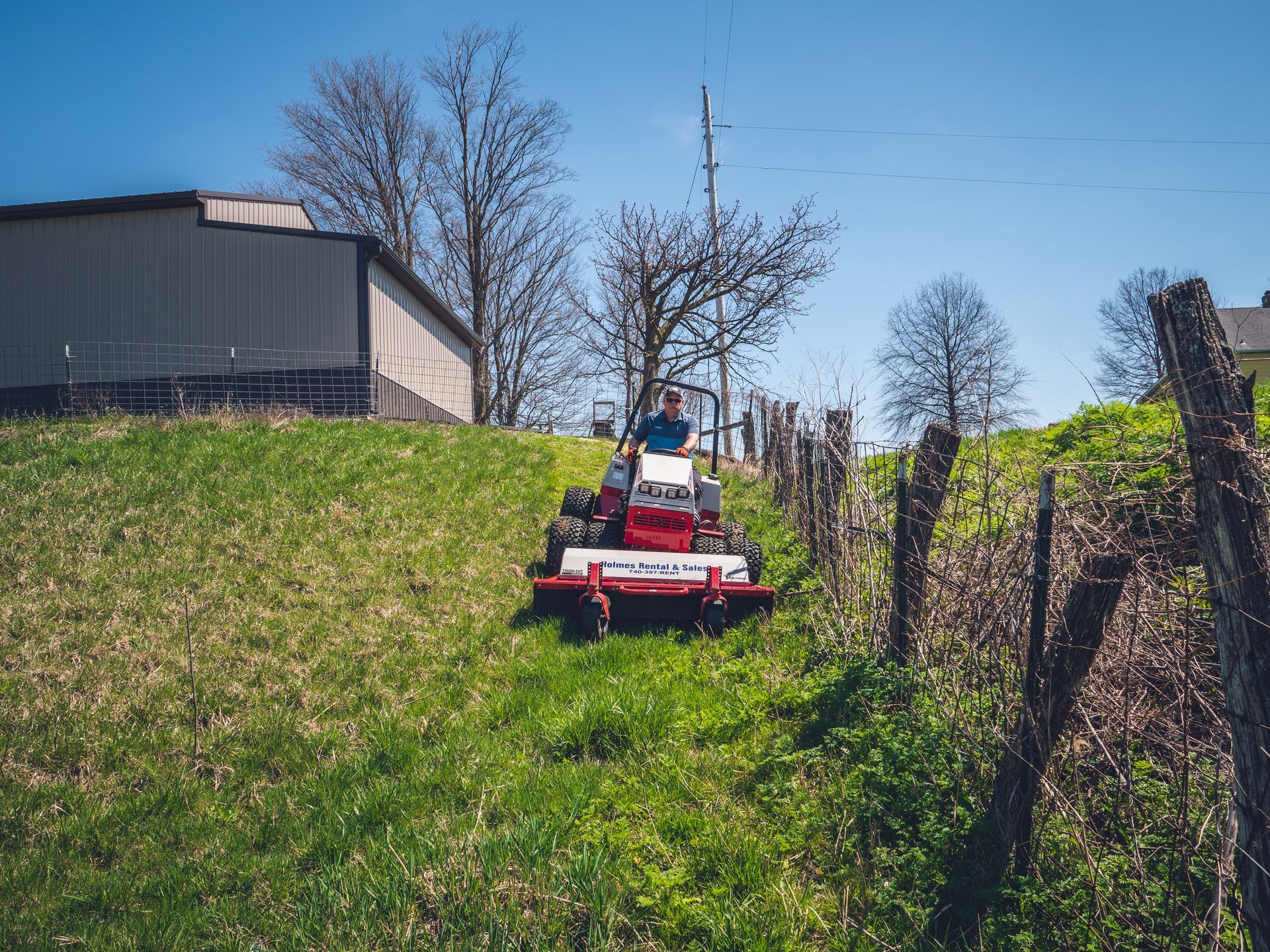 A man is riding a lawn mower down a hill.